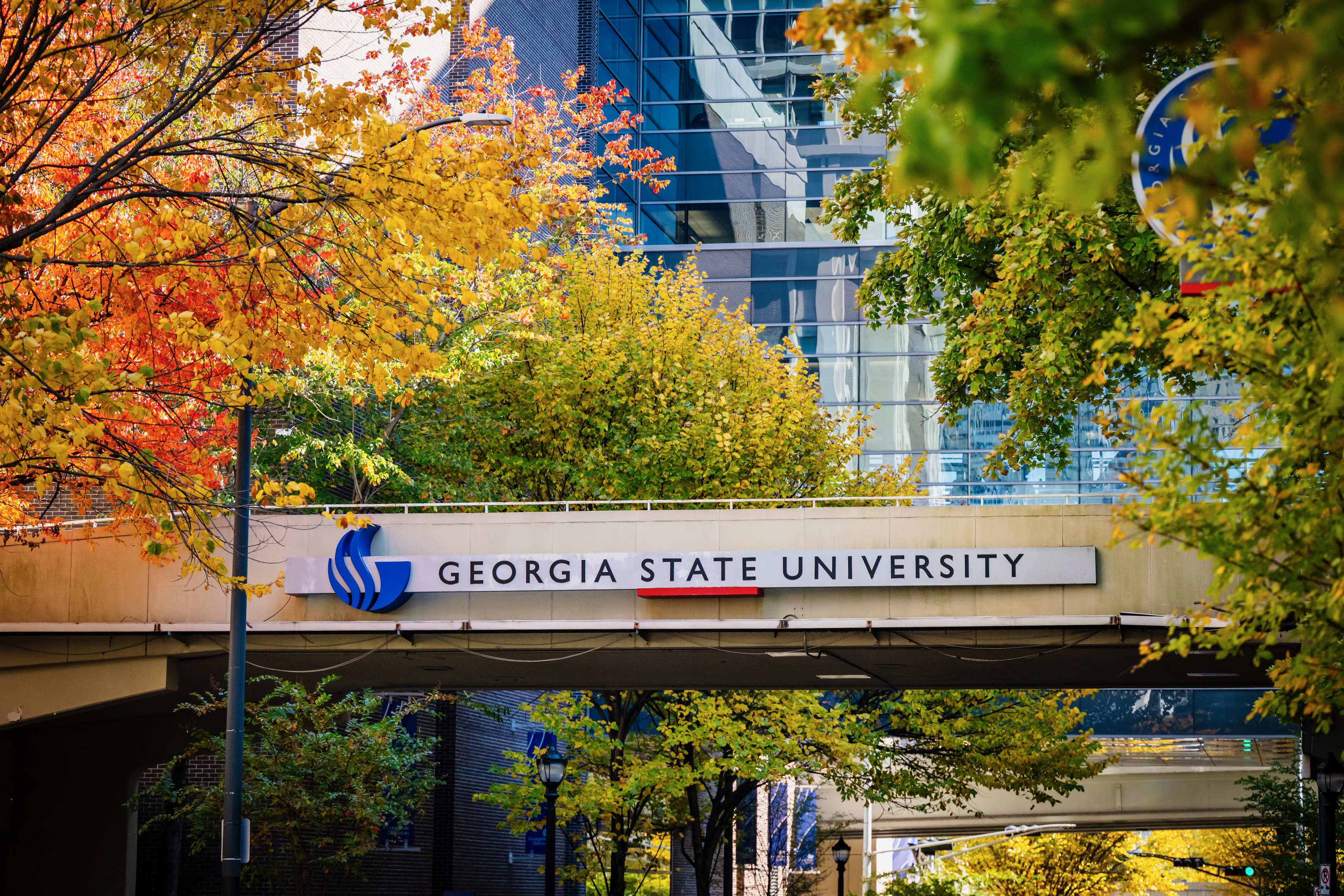 The Georgia State University sign on a downtown Atlanta campus walkway, framed by trees in fall color